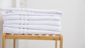 A stack of white towels on a wooden stool.