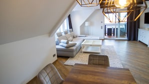 A modern loft apartment with a dining area, a sofa set, and a kitchen area. - Schiefer Suite Hotel & Apartment (Goslar)