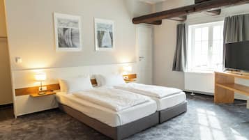 Ein Hotelzimmer mit Doppelbett, Nachttischen, einem Schreibtisch, einem Fernseher und Bildern an der Wand.