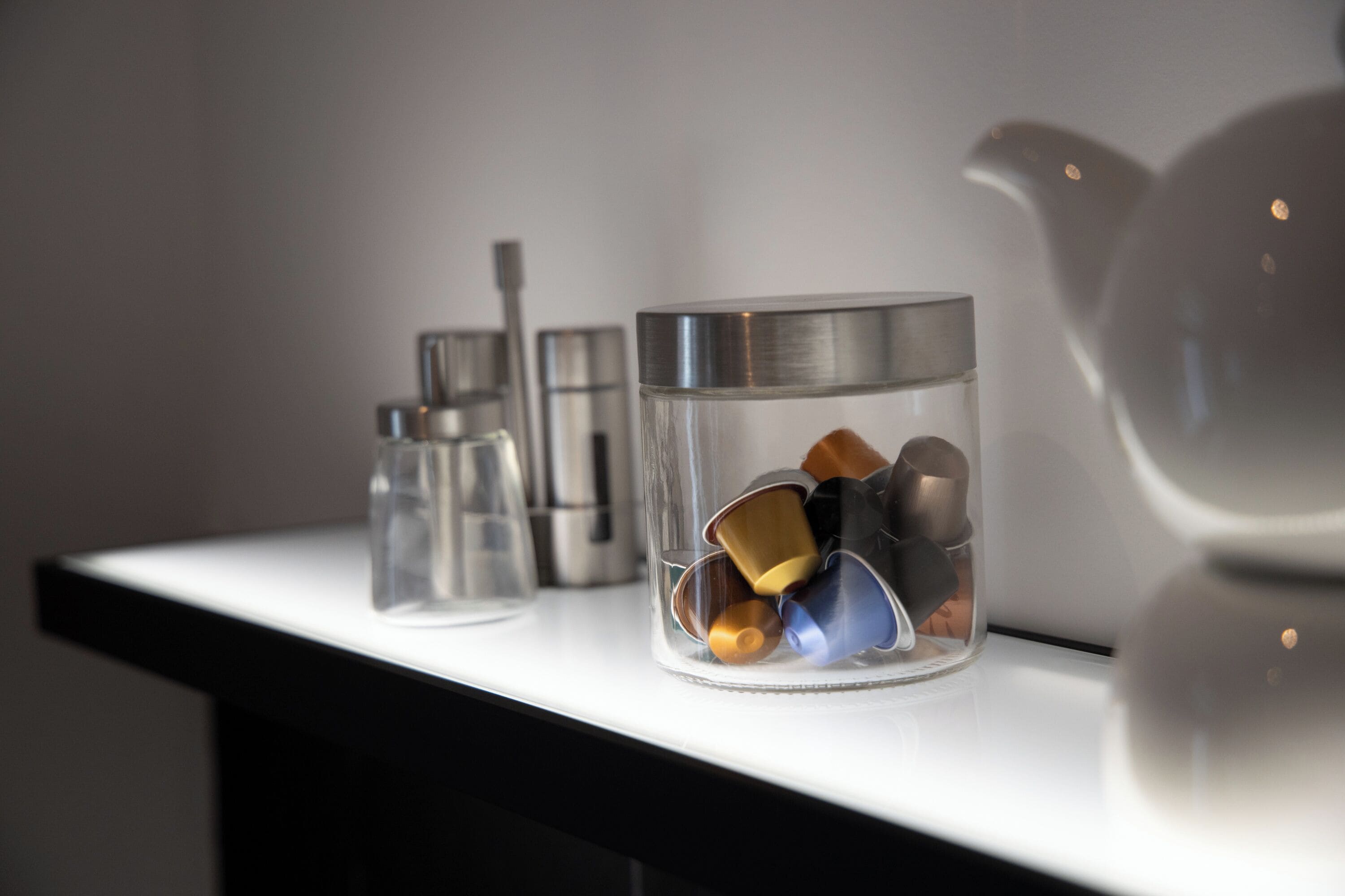 A clear glass container with various metal objects on a white surface.