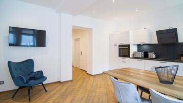 A modern kitchen with white cabinets, a wooden dining table, and a blue chair.