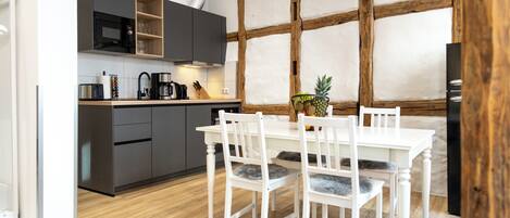 A modern kitchen with dark cabinets, a white dining table, and chairs.