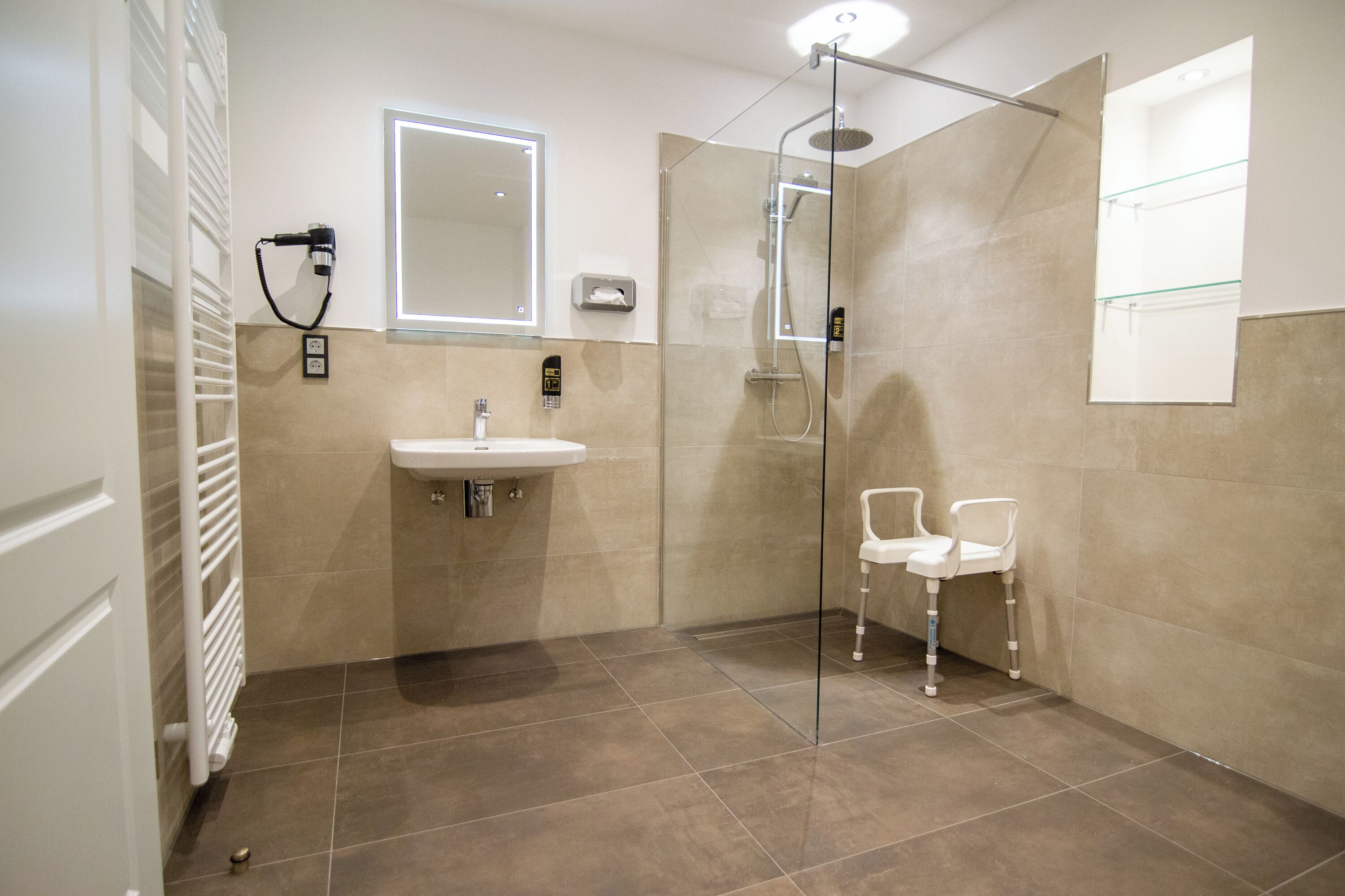 Een moderne badkamer met een douchecabine van glas, een wastafel en een spiegel.