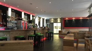 A modern bar area with a counter, stools, and seating. - Schiefer Suite Hotel & Apartment (Goslar)