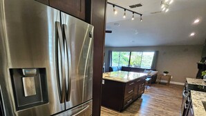 A modern kitchen with stainless steel appliances, wooden flooring, and a large island. - Florida Life on the water with game room, heated pool, kayaks +
Pet friendly!! (Palm Harbor)