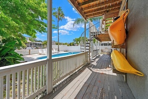 A wooden deck with a pool, white railings, and a yellow planter.