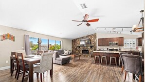 A spacious living area with a stone fireplace, a dining area with wooden flooring, and a kitchen with modern appliances. - Florida Life on the water with game room, heated pool, kayaks +
Pet friendly!! (Palm Harbor)