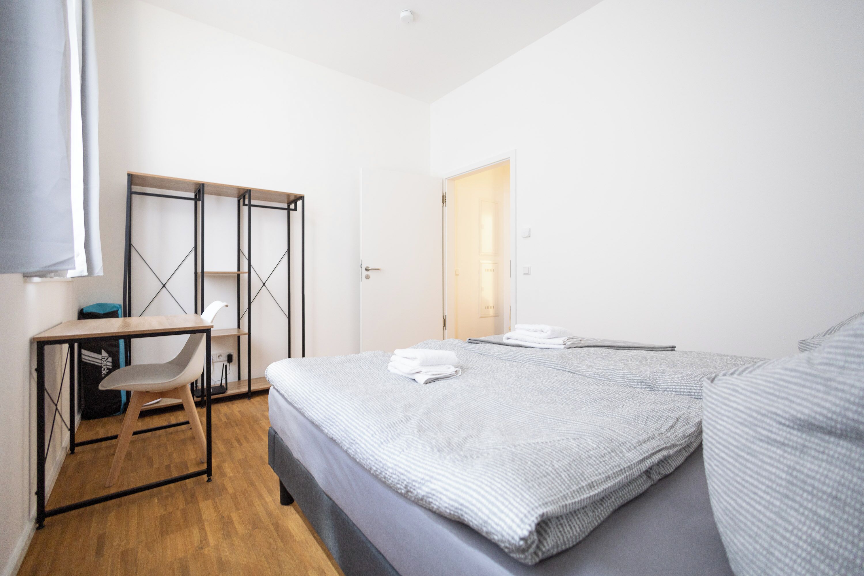 A bedroom with a bed, a desk, a chair, and a wardrobe.