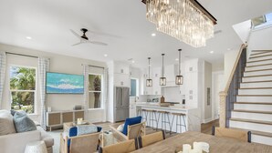 Une cuisine moderne avec des armoires blanches, un grand îlot central et des luminaires suspendus.