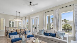 Un salon spacieux avec un canapé beige, des fauteuils bleus et un coin repas.