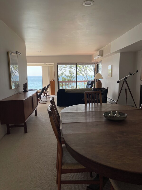 Ein Zimmer mit Esstisch, Stühlen, einer Couch, einem Teleskop und Meerblick.