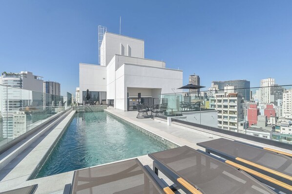 Een zwembad op het dak met een helder uitzicht op de stadsplattegrond, moderne architectuur en een glazen balustrade.