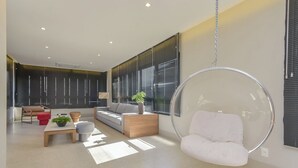 A modern living room with a hanging chair, a sofa, a coffee table, and a plant. - Safety and comfort: 2 beds, up to 3 people. New (Campos Elíseos São Paulo)