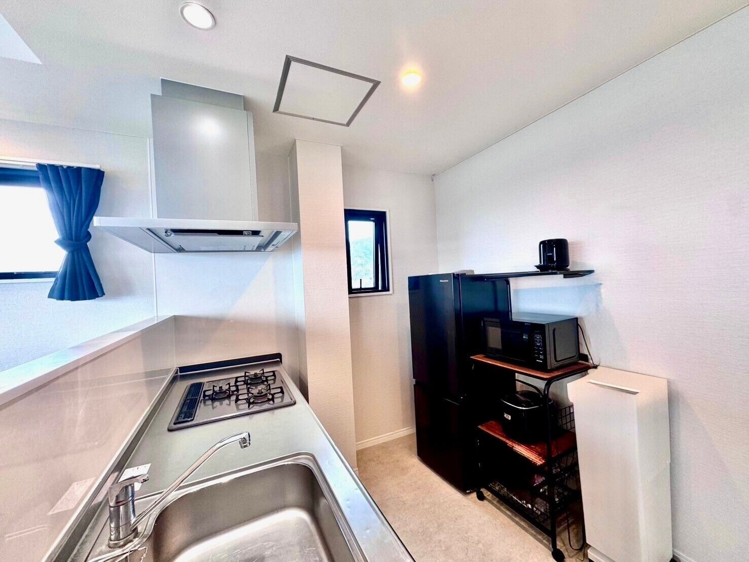 A compact kitchen with a gas stove, sink, microwave, and a small refrigerator.