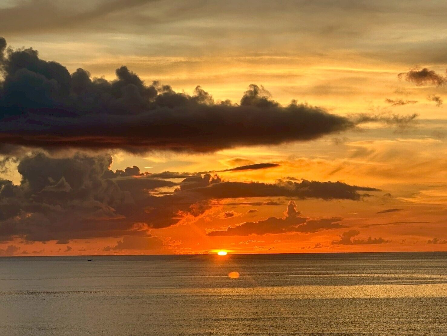 A sunset over a calm sea with a clear horizon.