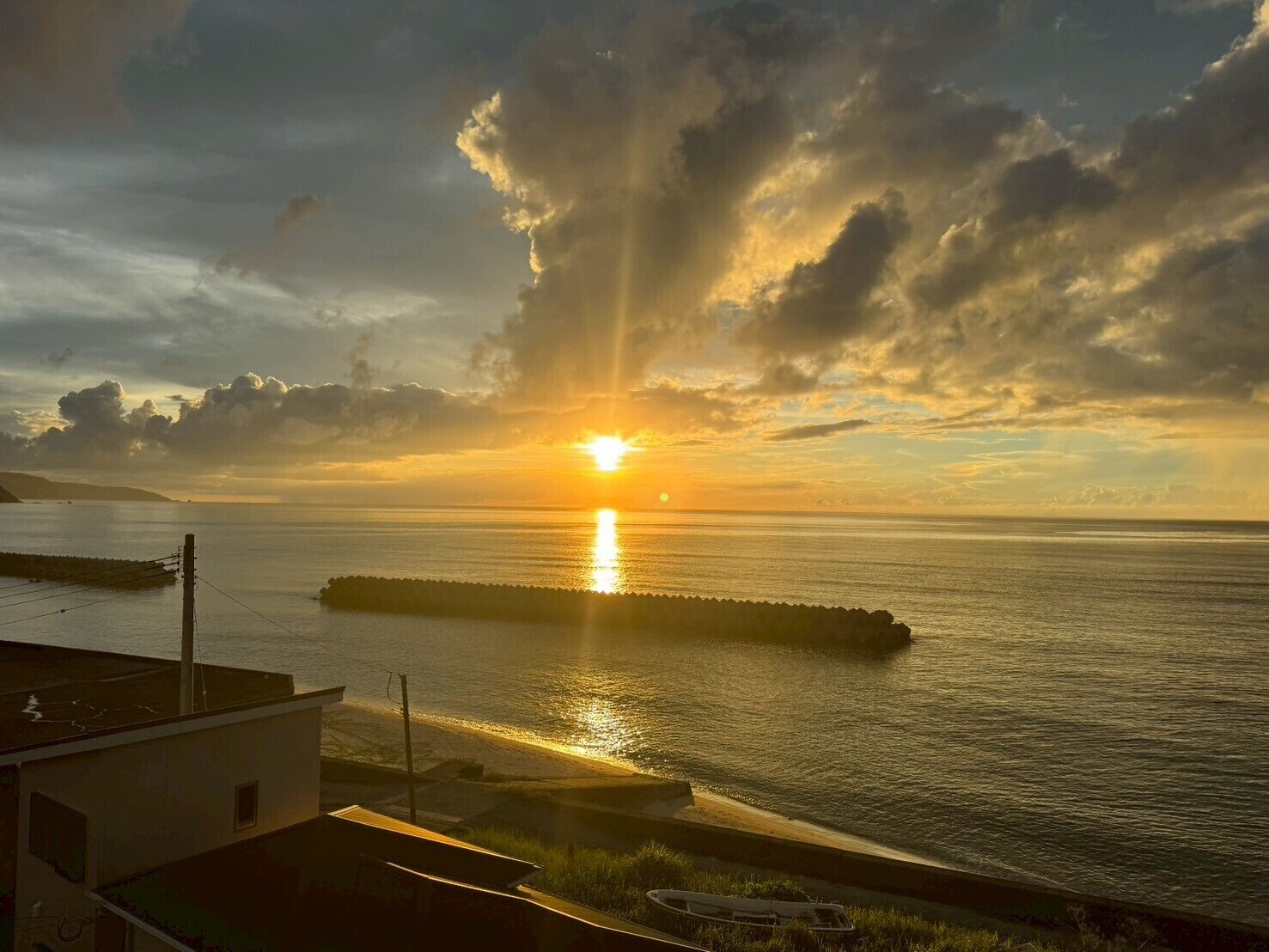 A sunset over a calm sea with a pier extending into the water.