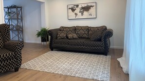 Ein Wohnzimmer mit einem gemusterten Sofa, einem gemusterten Sessel, einer Weltkarte an der Wand und einem Holzboden.