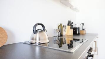 A modern kitchen with a kettle on a countertop, a knife block, and a cork coaster.