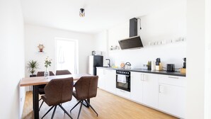 Una cocina moderna con armarios blancos, una mesa de comedor de madera y dos sillas marrones.