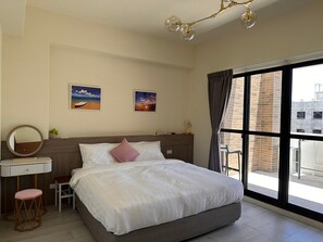 A hotel room with a large bed, a bedside table with a mirror, a small stool, and two framed pictures on the wall. - SeaWave (Magong)