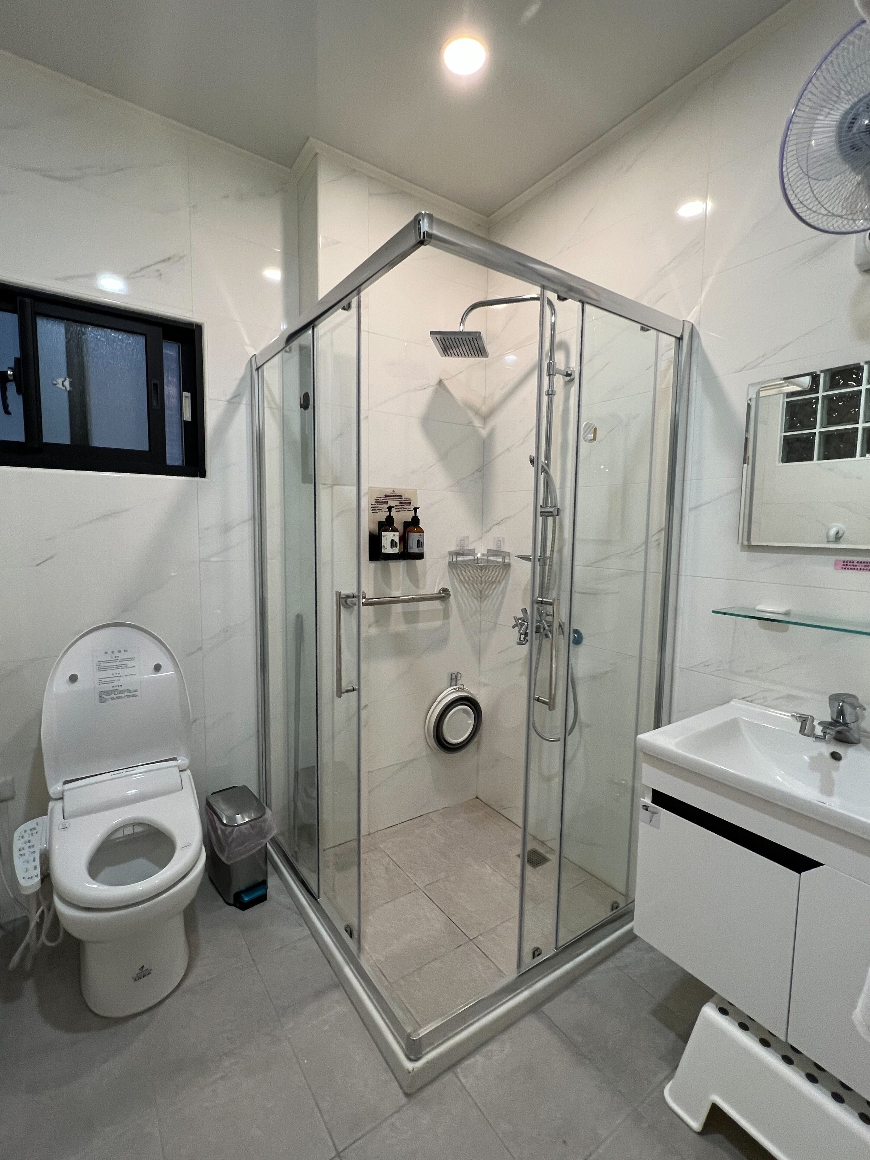 Un baño moderno con ducha acristalada, inodoro y lavamanos.