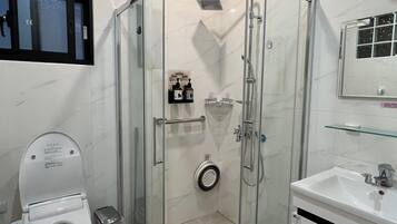 Un baño moderno con ducha acristalada, inodoro y lavamanos.