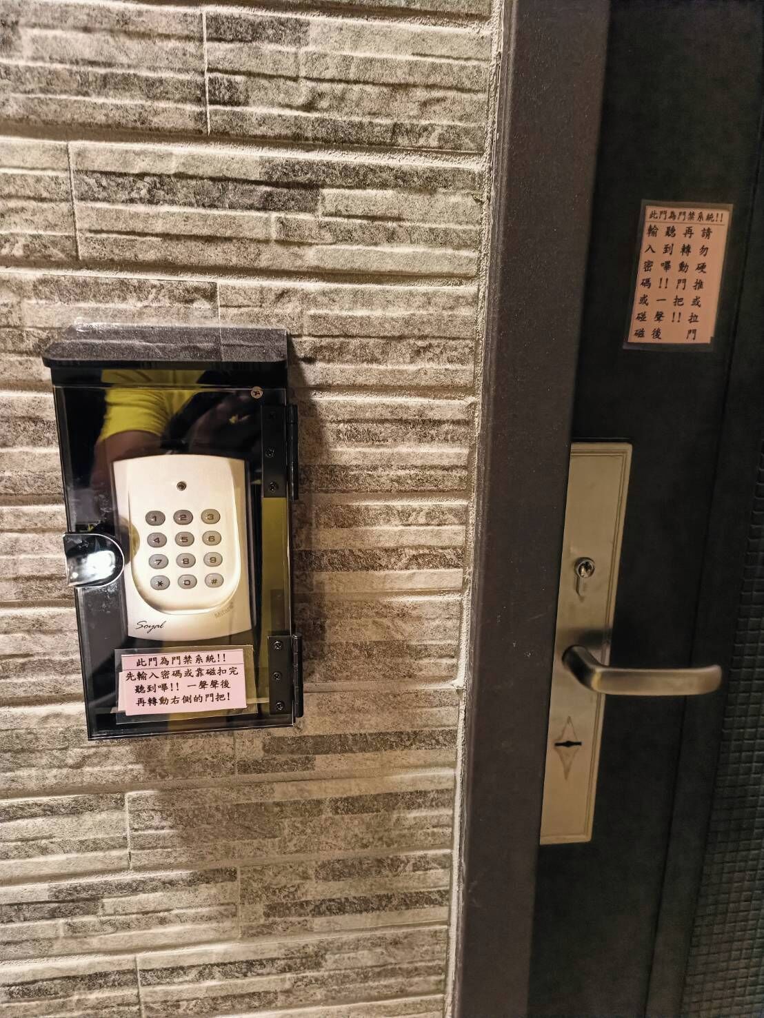 A wall-mounted intercom system with a keypad and a door handle.