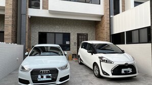 Two white cars parked in front of a modern building with a brick facade and large windows. - SeaWave (Magong)