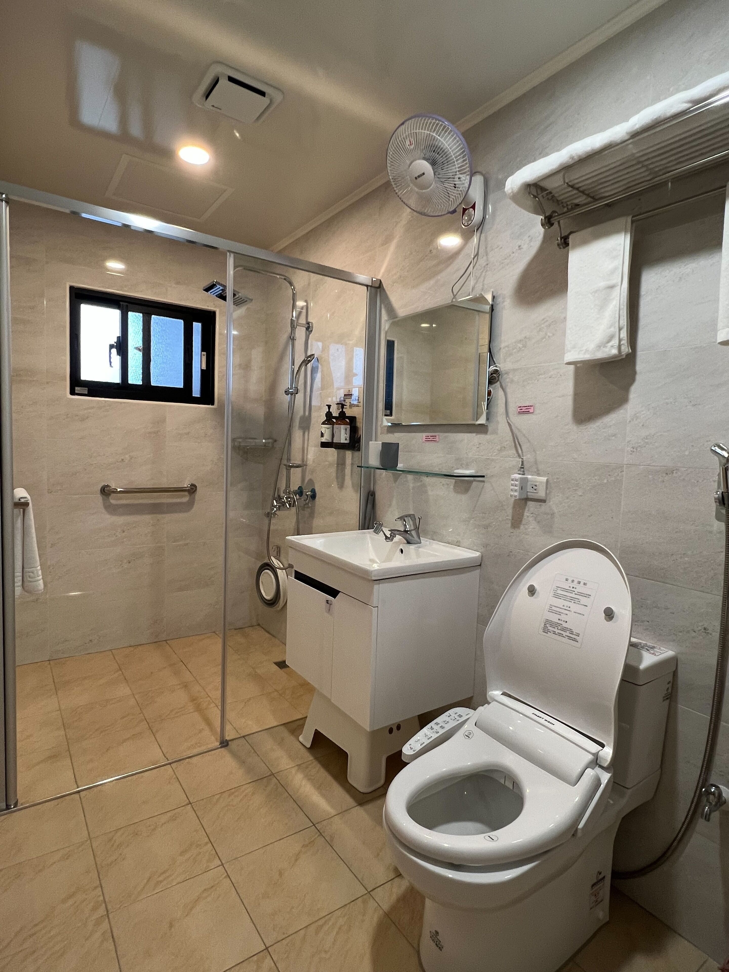 A modern bathroom with a glass-enclosed shower, a toilet, a sink, and a mirror.