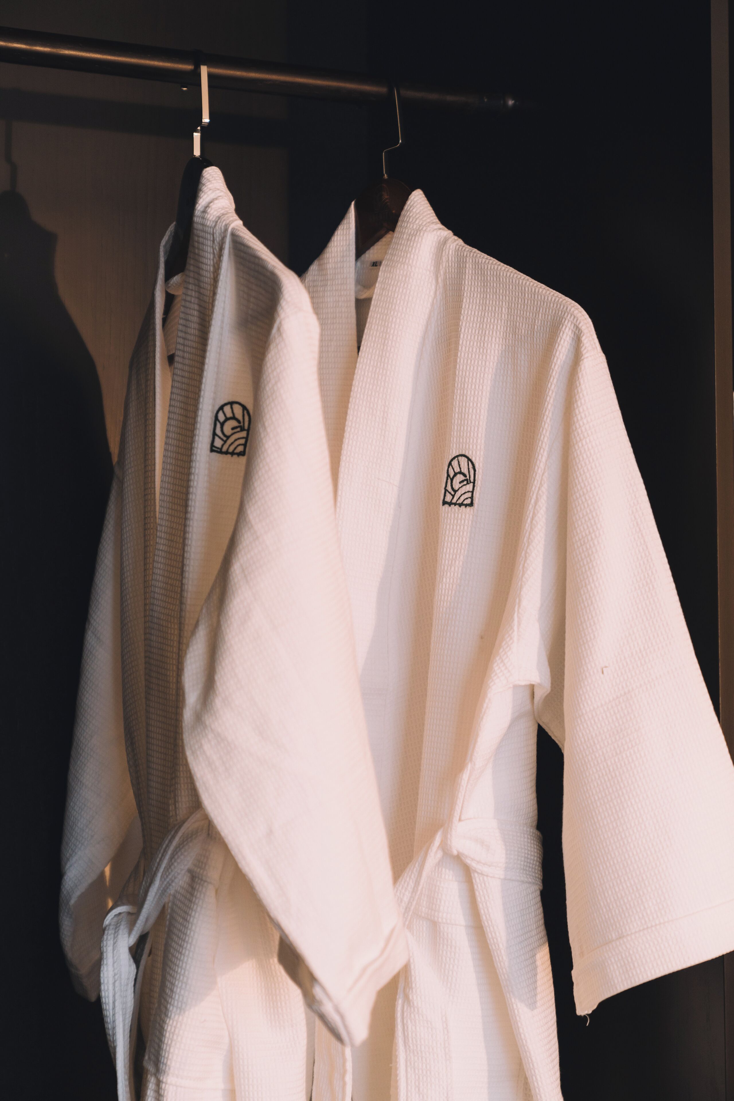 Two white robes hanging on a rack.