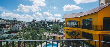 Edificio amarillo con balcón que da a una piscina y una zona residencial.