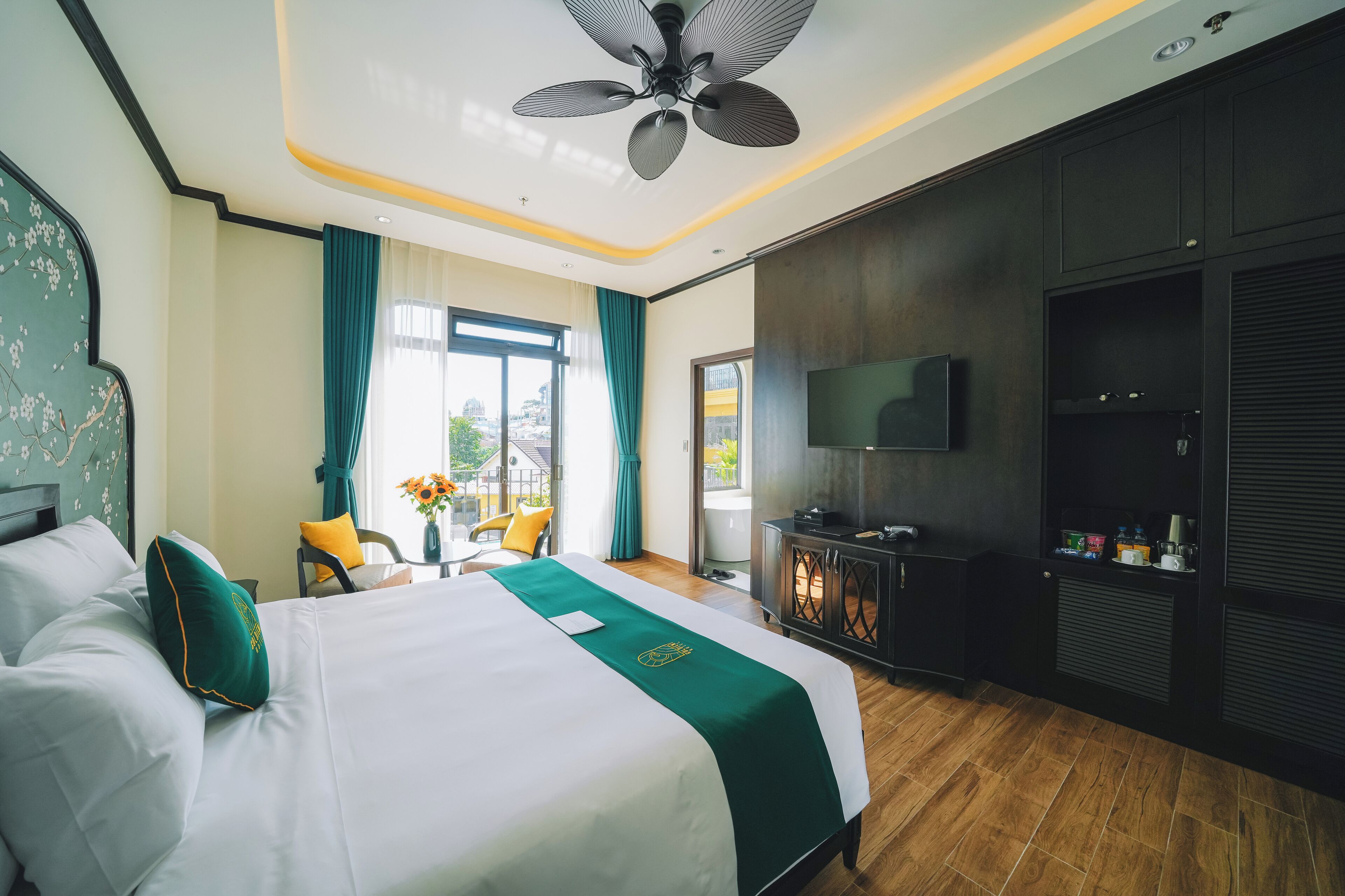 A hotel room with a bed, a TV, a desk, and a view of the outdoors.