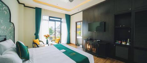 A hotel room with a bed, a TV, a desk, and a view of the outdoors.