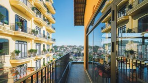 A balcony with a view of a cityscape, featuring multiple balconies with railings and potted plants. - Goldient Boutique Hotel (Xuan Huong - Da Lat)