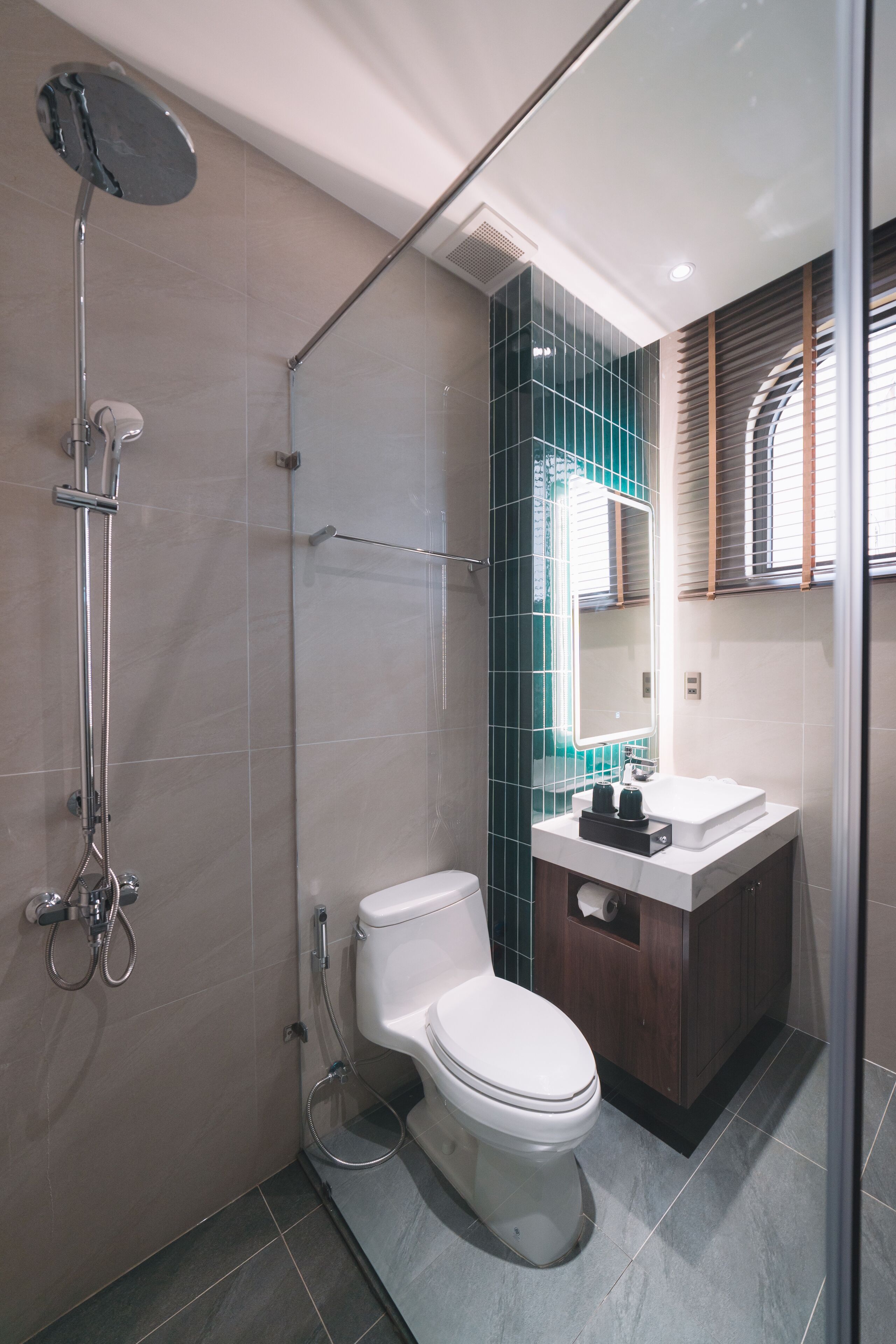 A modern bathroom with a glass-enclosed shower, a white toilet, and a vanity with a mirror.