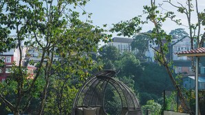 A pool area with a wicker chair and a view of buildings in the background. - Goldient Boutique Hotel (Xuan Huong - Da Lat)