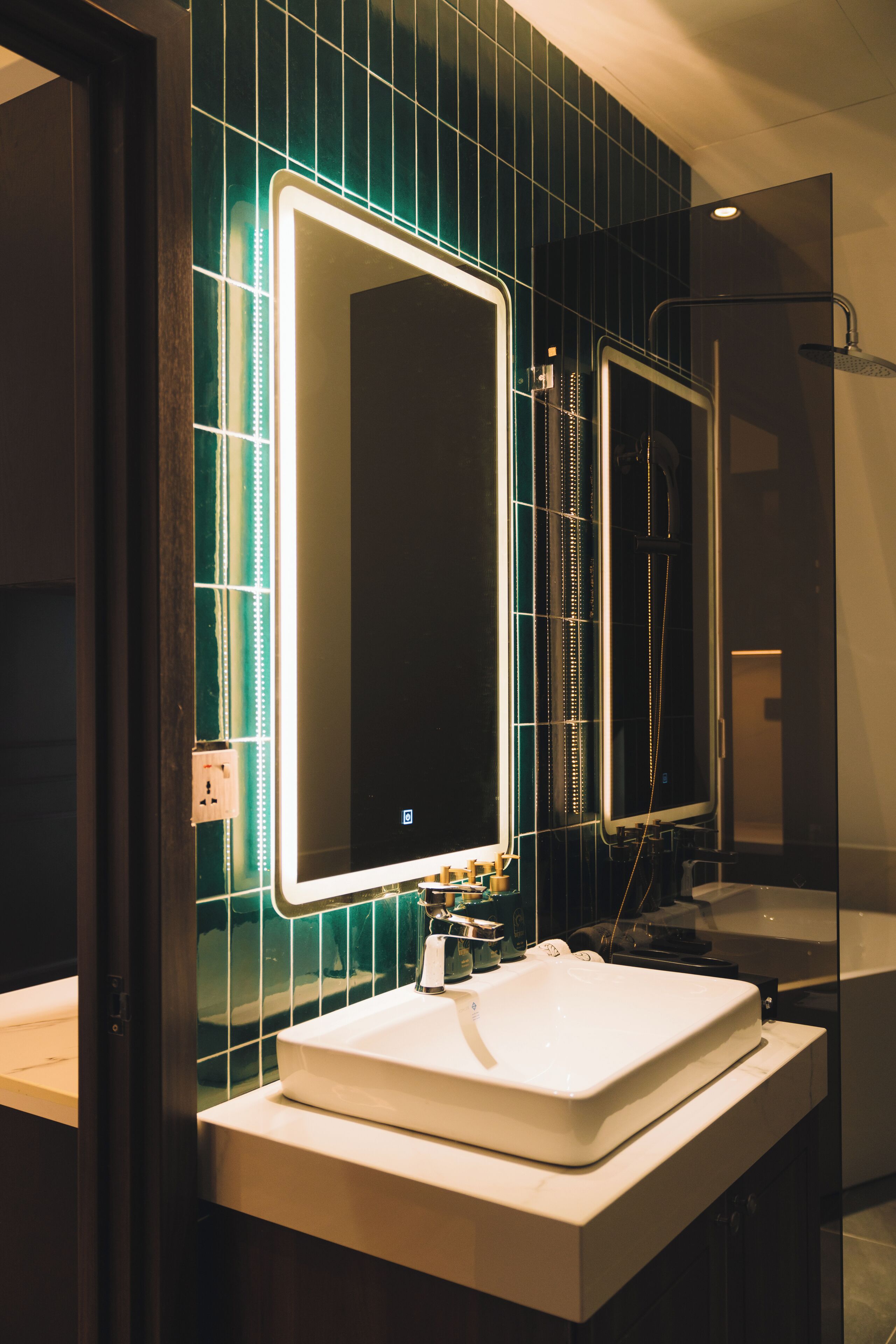 A bathroom with a white sink, a mirror with LED lights, and a shower area.