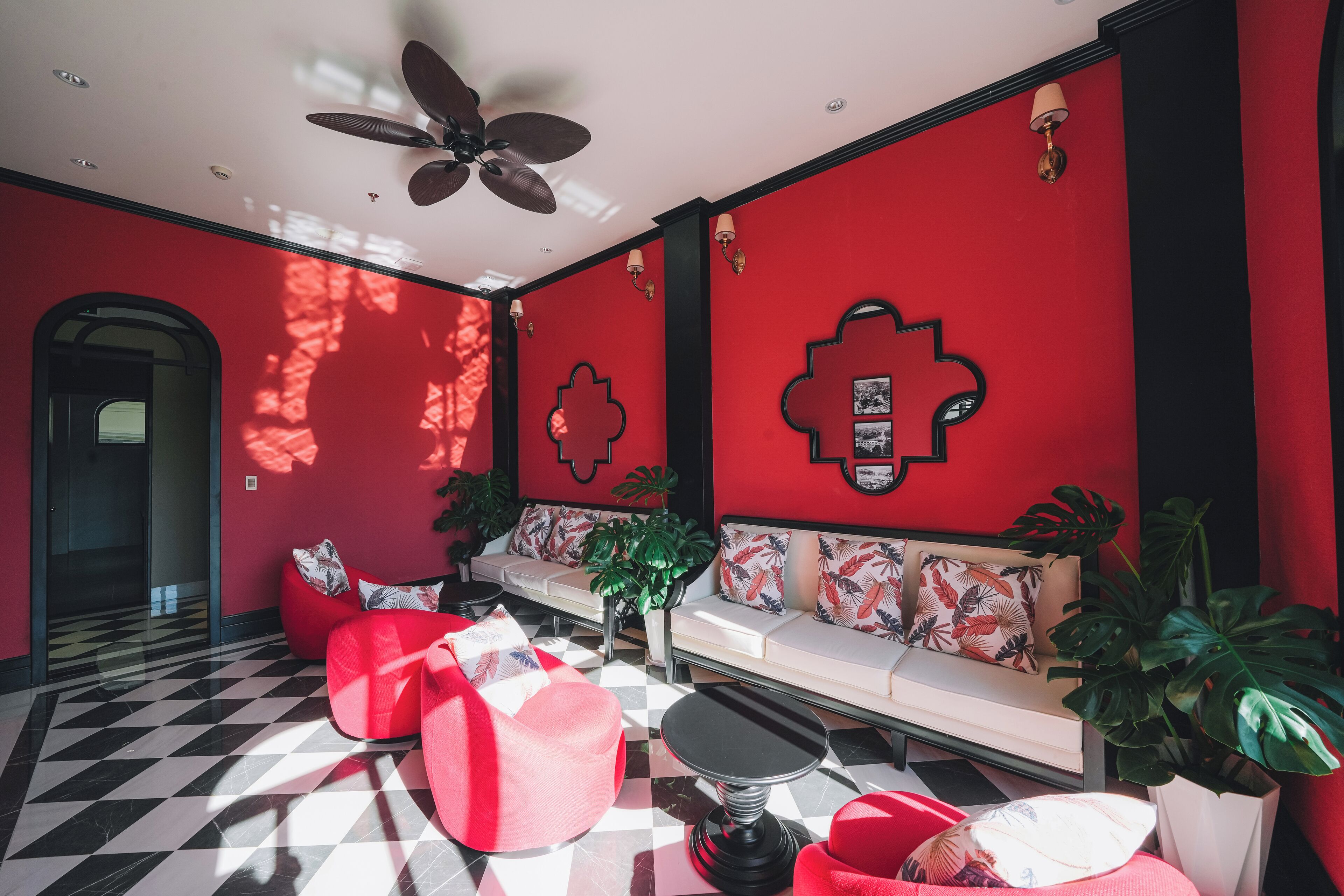 A modern interior with a red and black checkered floor, a sofa with patterned cushions, and a ceiling fan.