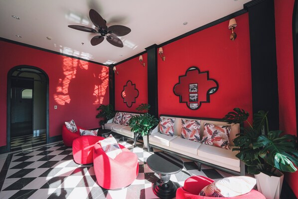 A modern interior with a red and black checkered floor, a sofa with patterned cushions, and a ceiling fan. - Goldient Boutique Hotel (Xuan Huong - Da Lat)