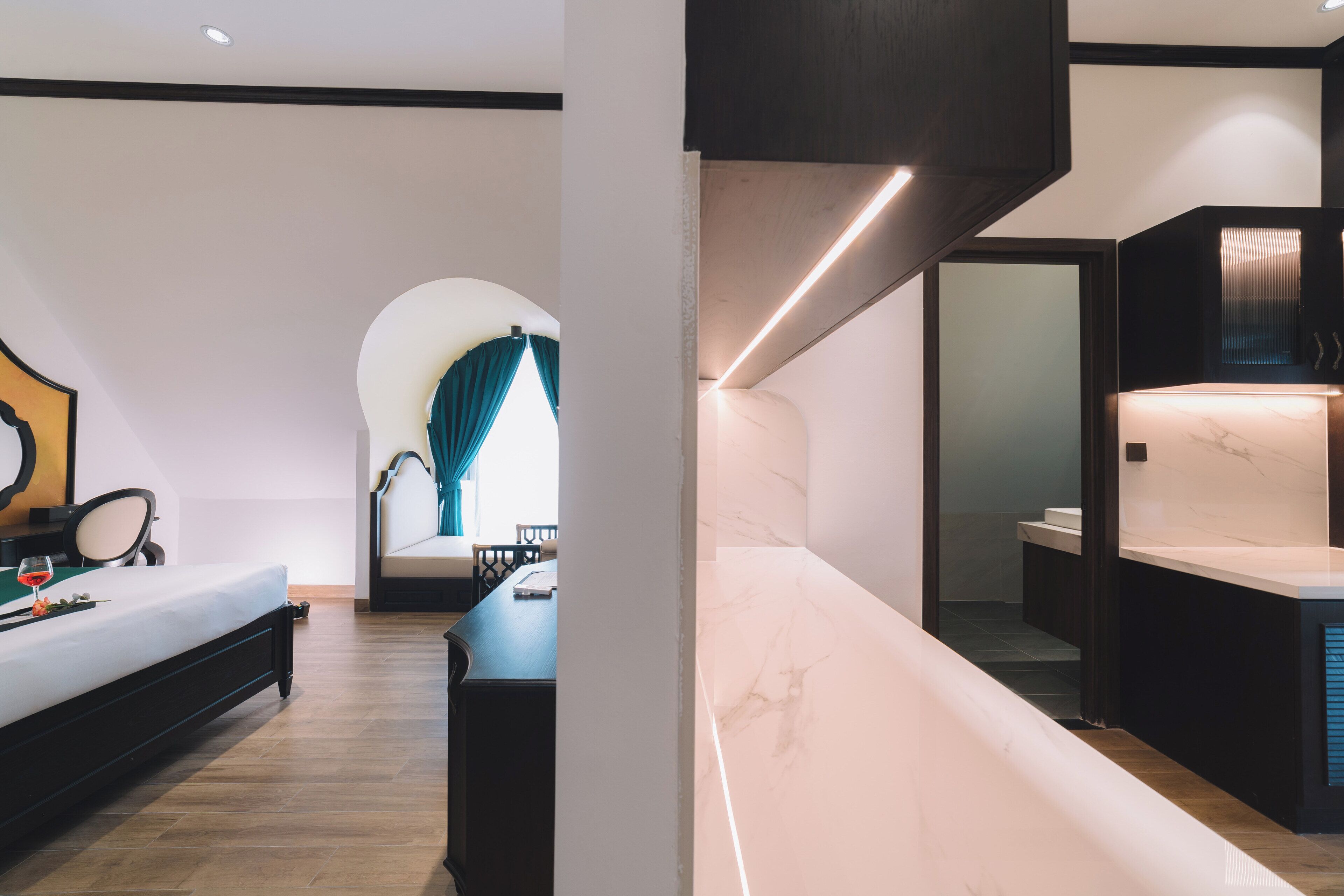 A modern hotel room with a bed, a desk, and a bathroom with a marble countertop.