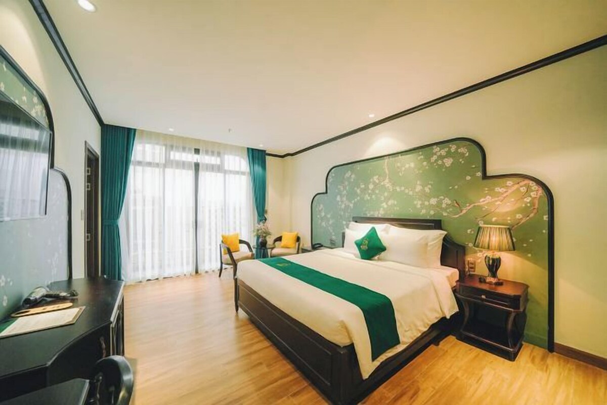 Une chambre d’hôtel comprenant un lit, une table de chevet, une lampe et un bureau avec une chaise.
