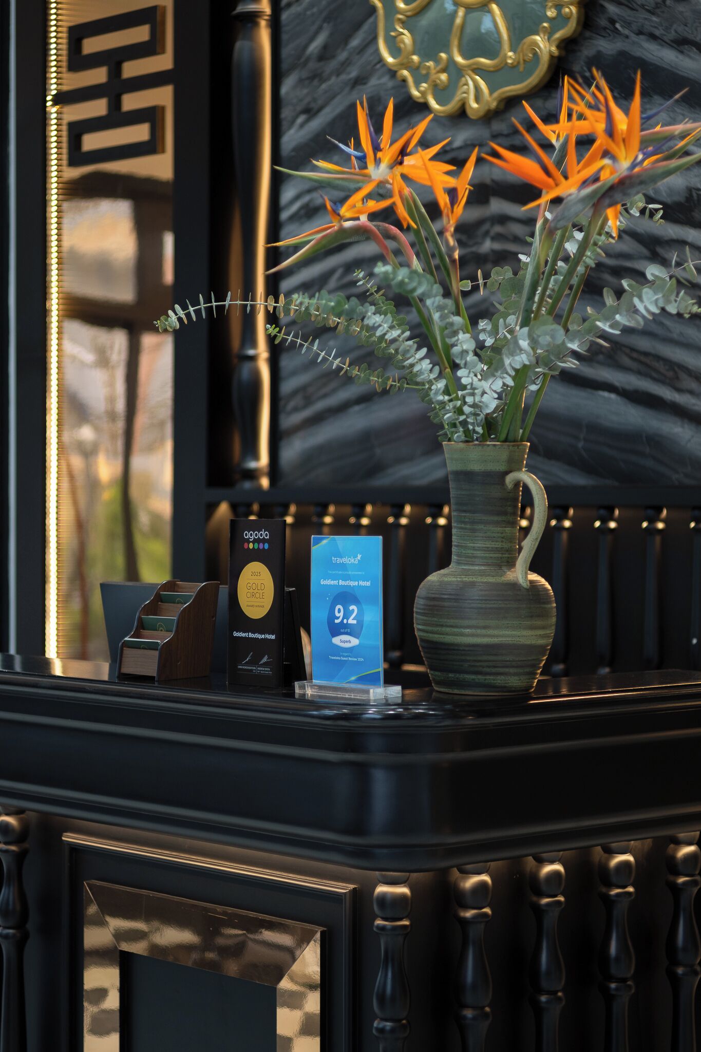 A reception desk with a vase of flowers, a gold plaque, and a sign indicating a 9.2 rating.