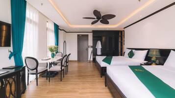 Une chambre d’hôtel équipée d’un lit, d’un bureau, d’une chaise, d’une télévision et d’un ventilateur de plafond.