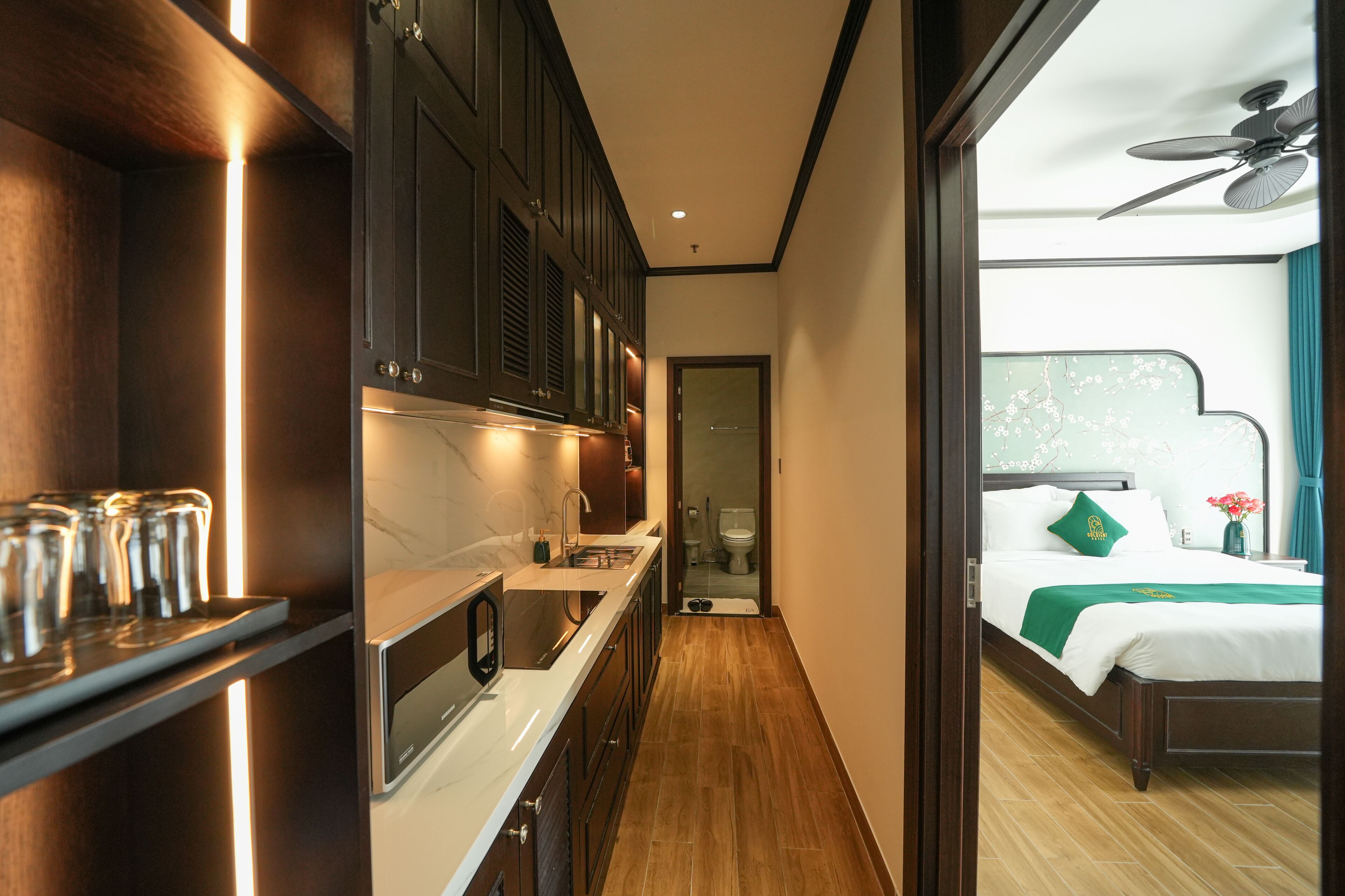 A modern hotel room with a kitchen area, a bathroom, and a bedroom.