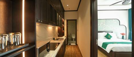 A modern hotel room with a kitchen area, a bathroom, and a bedroom.