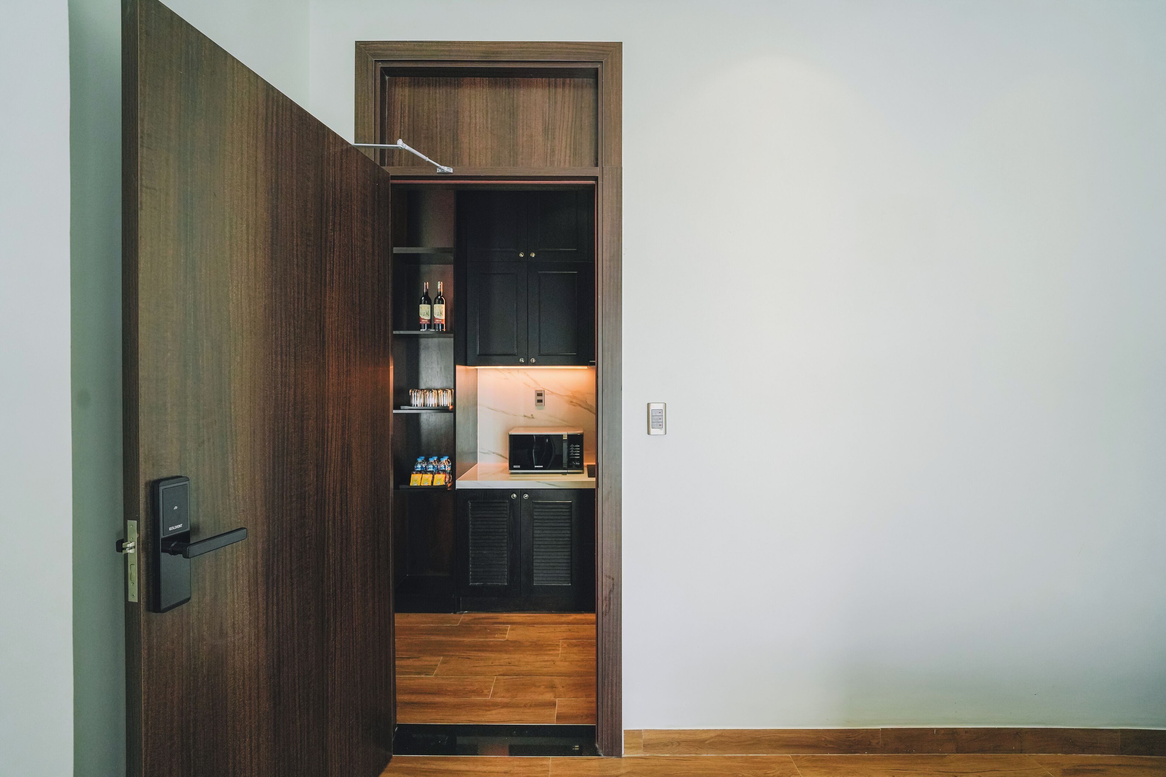Una cucina moderna con mobili in legno scuro, un forno a microonde integrato e un piccolo bancone.