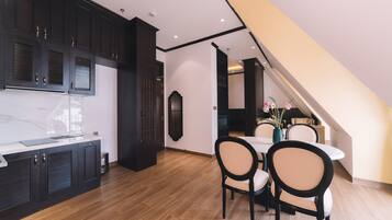 A modern kitchen with dark cabinetry, a marble countertop, and a dining area with a table and chairs.