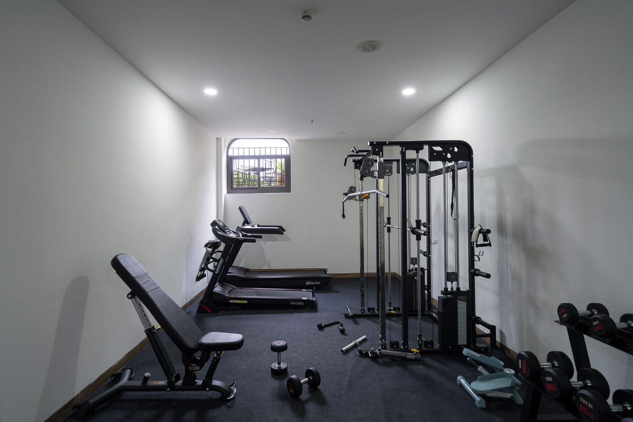 Une salle de sport équipée de tapis de course, d’un banc de musculation, d’haltères et d’un support à squats.