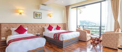 A hotel room with two beds, a sofa, a desk, and a large window with a view.