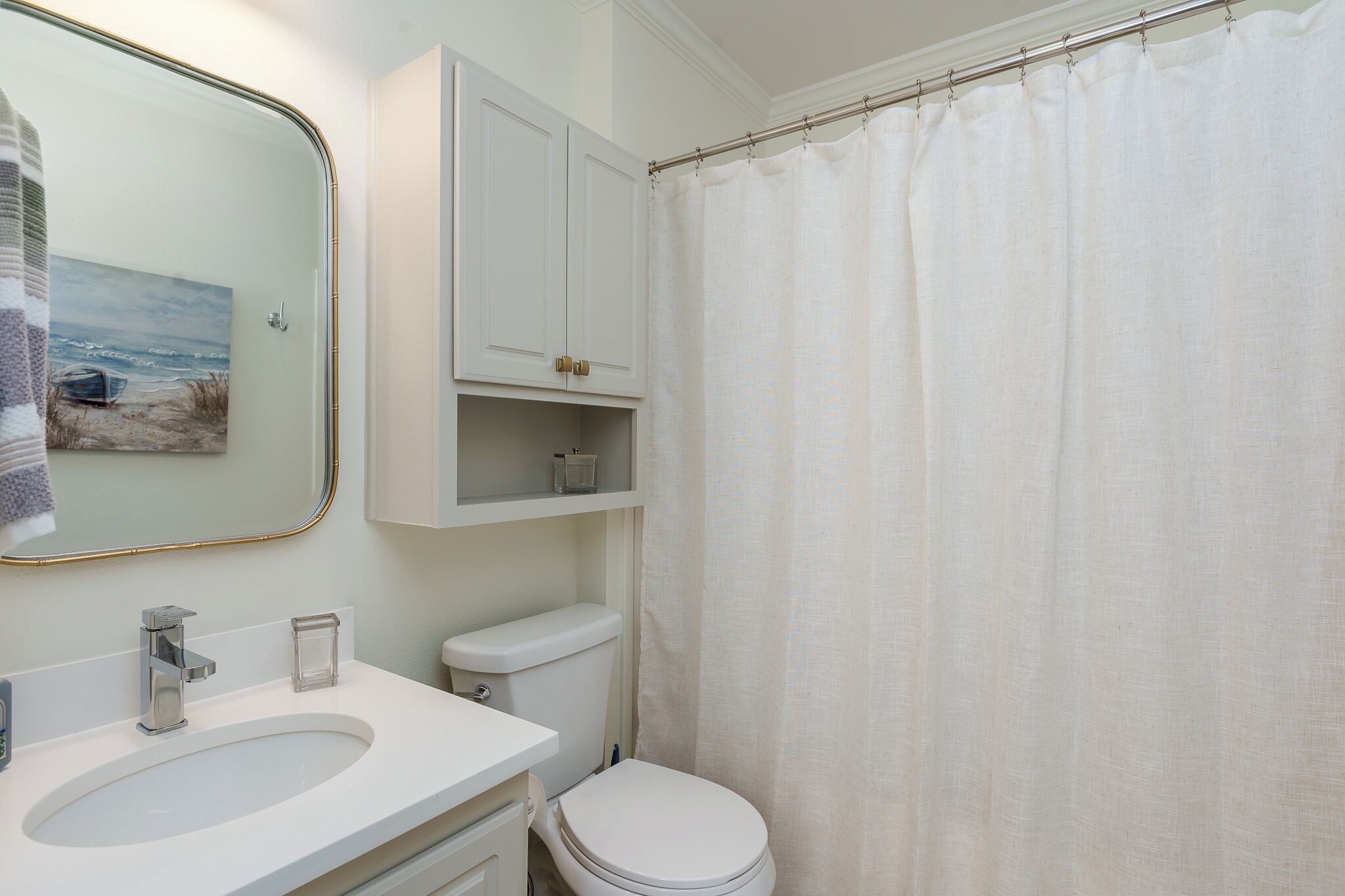 Une salle de bain avec un lavabo blanc, des toilettes et un rideau de douche.